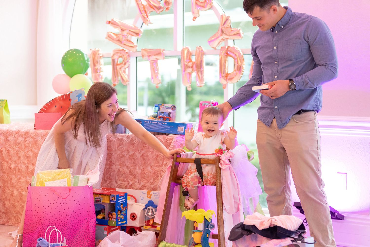 Birthday party scene with pink decorations and presents being opened.