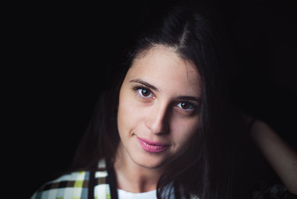 Portrait of a woman on a black background leaning to the side and backwards