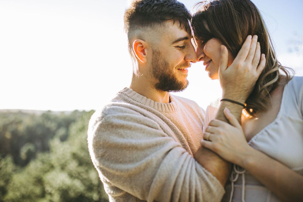 Intimate moment between couple sharing tender embrace in warm sunlight.
