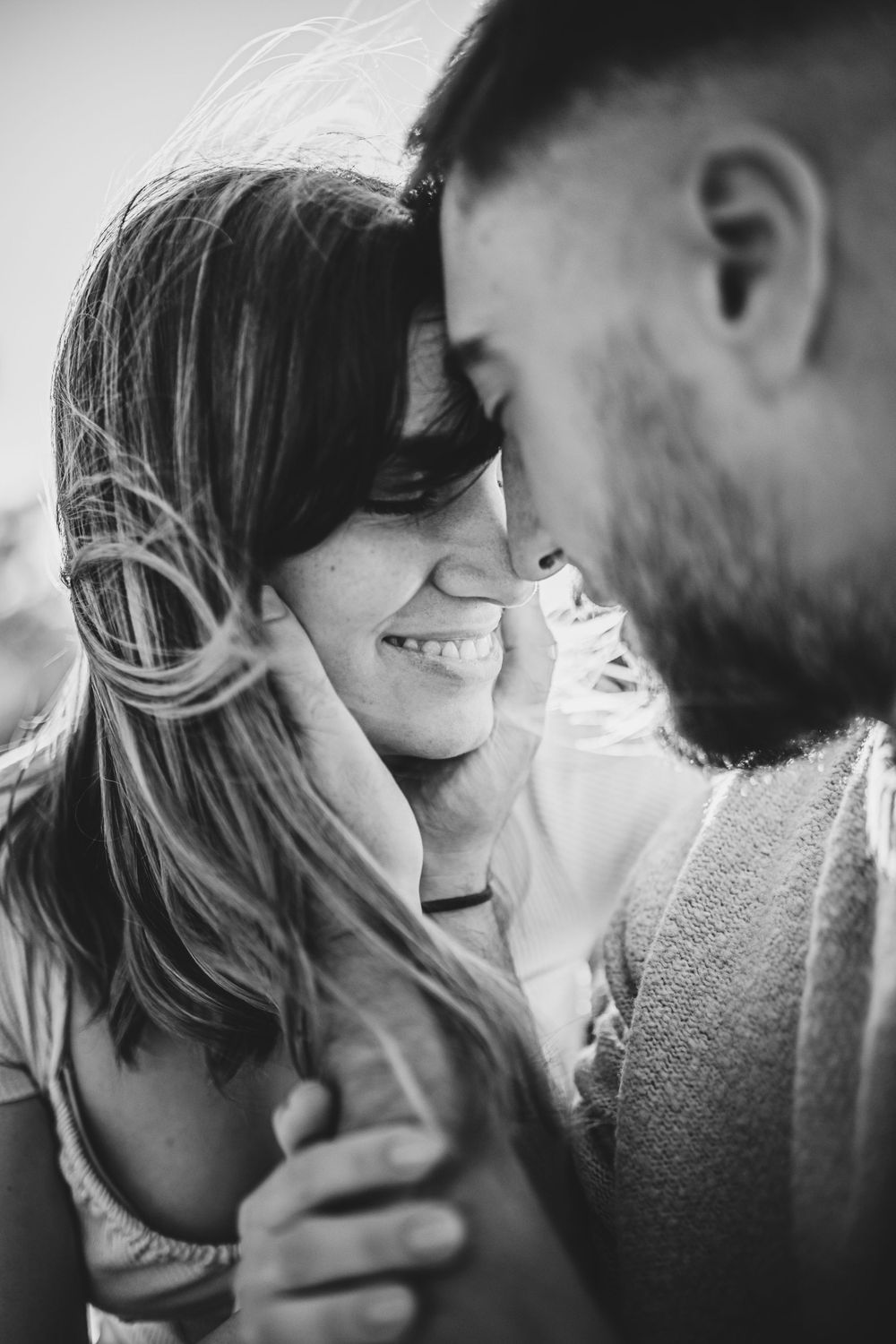 Black and white portrait of couple sharing intimate moment outdoors.