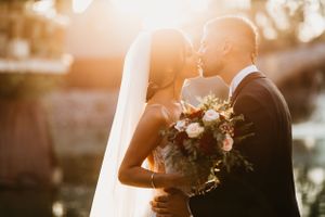 A romantic sunset wedding portrait capturing a tender moment with a floral bouquet.
