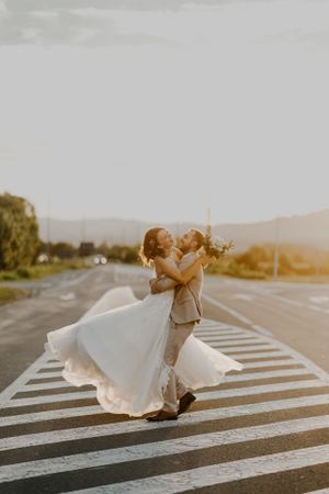 Romantic wedding couple dancing on crosswalk during golden hour sunset.