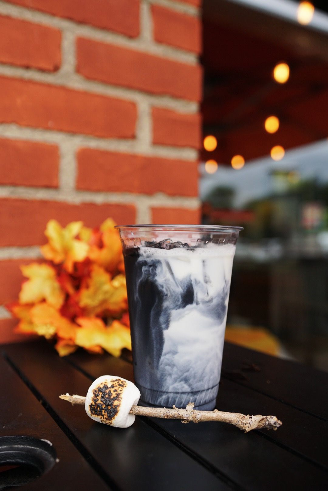 Smoky craft cocktails with garnish against brick wall with autumn decor.