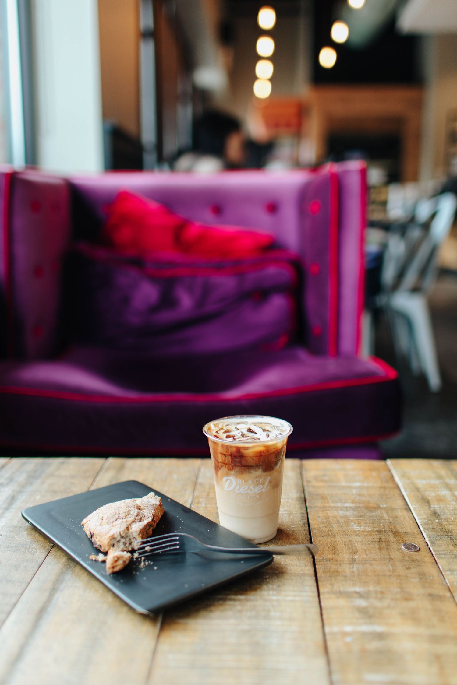Dessert plates and drinks arranged on wooden table with purple ambient lighting.