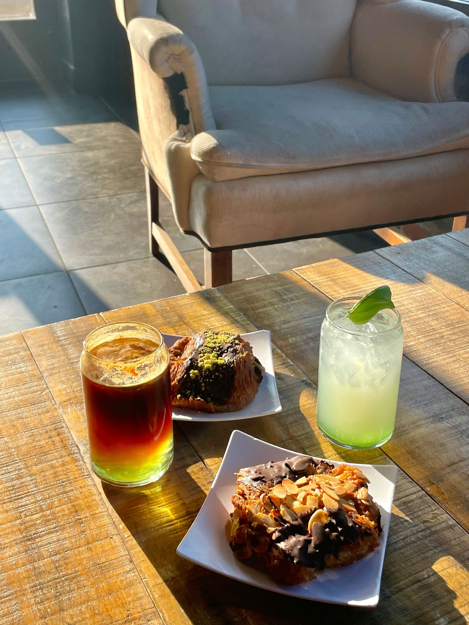 Desserts and colorful cocktails served on wooden table in casual dining setting.