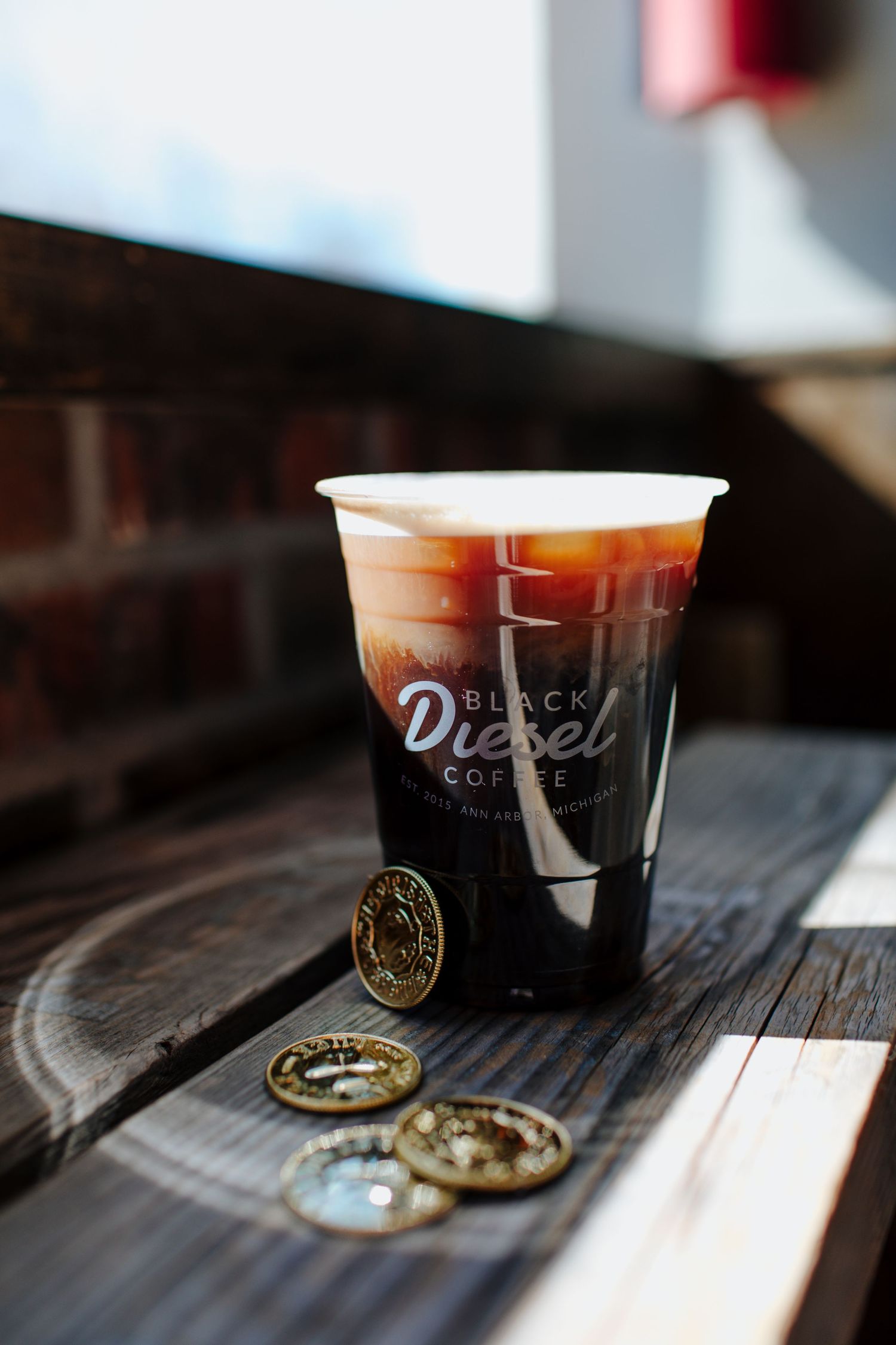 Coffee cups with brand logo on dark wooden surface showing drink progression.