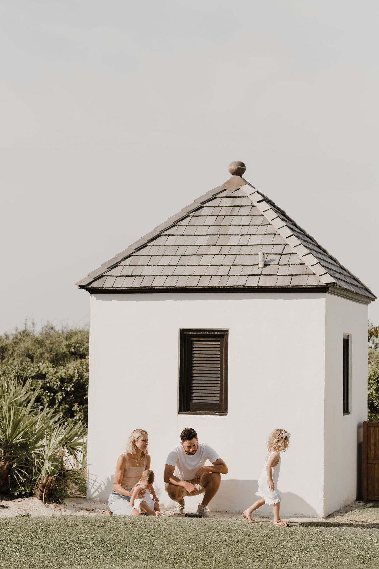 A sequence showing playful interaction near a small white beach house with palm trees.