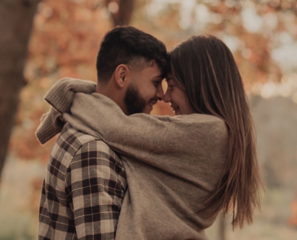 A tender autumn moment between a couple wearing cozy sweaters.