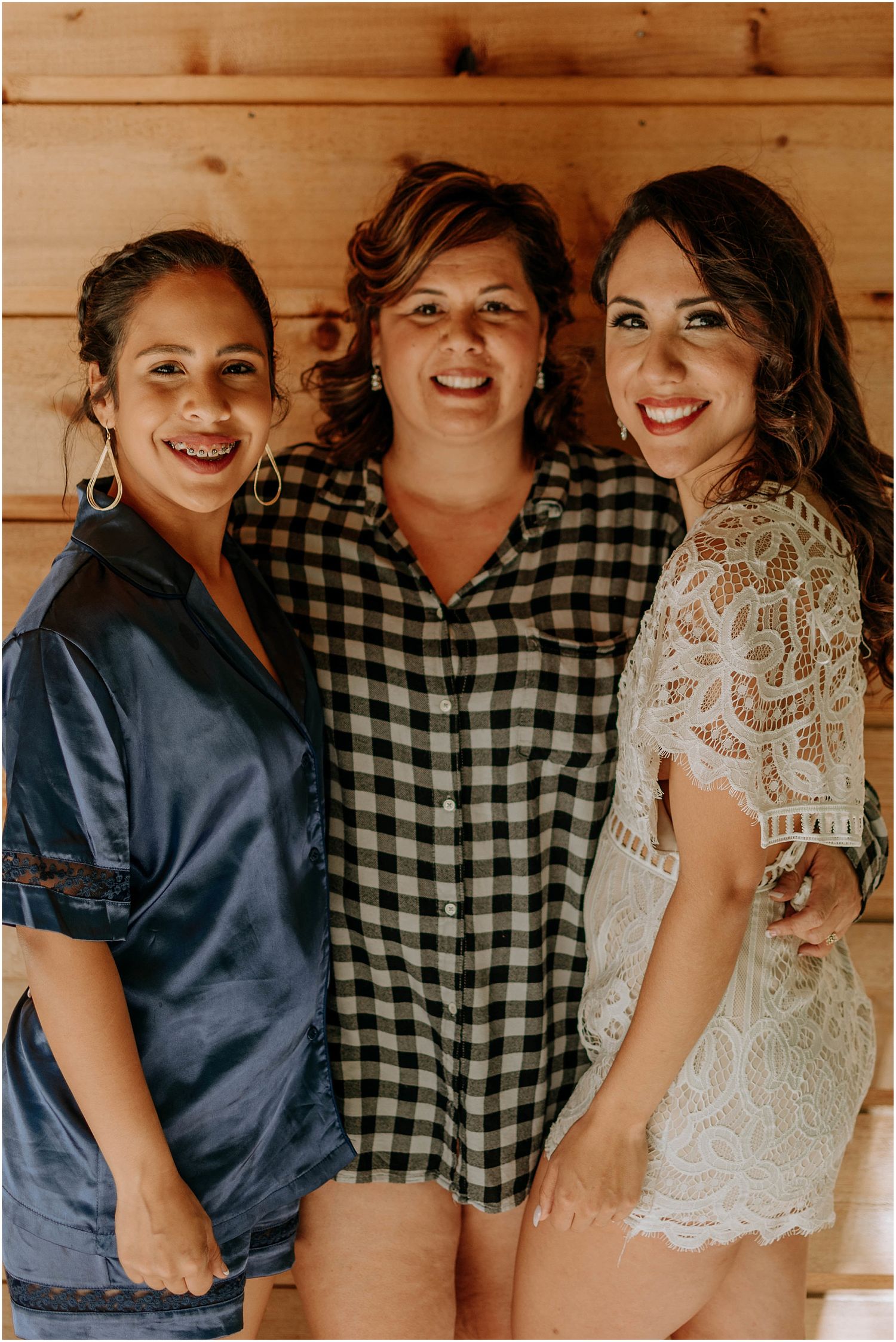 Friends pose together during wedding preparations in rustic wood cabin.