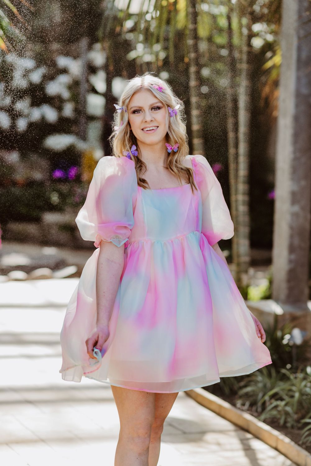 A dreamy pastel dress with puff sleeves is showcased in a sunlit garden pathway.
