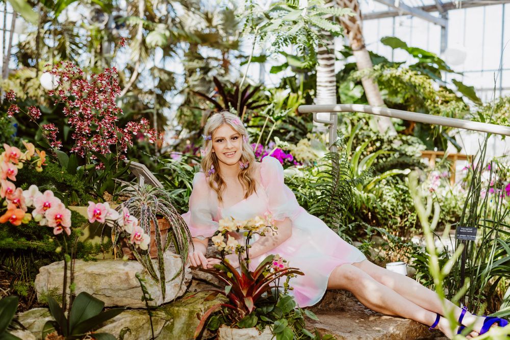 Greenhouse photoshoot featuring tropical plants and flowers in a bright indoor setting.