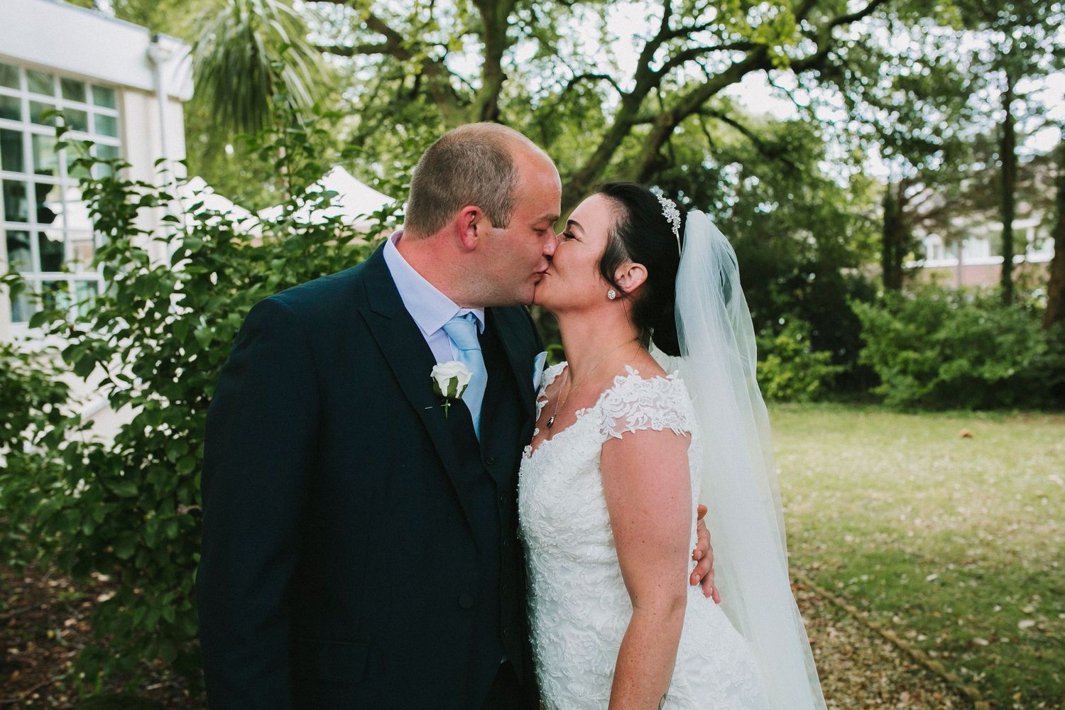 Wedding couple shares intimate moments in an outdoor garden setting with natural lighting.