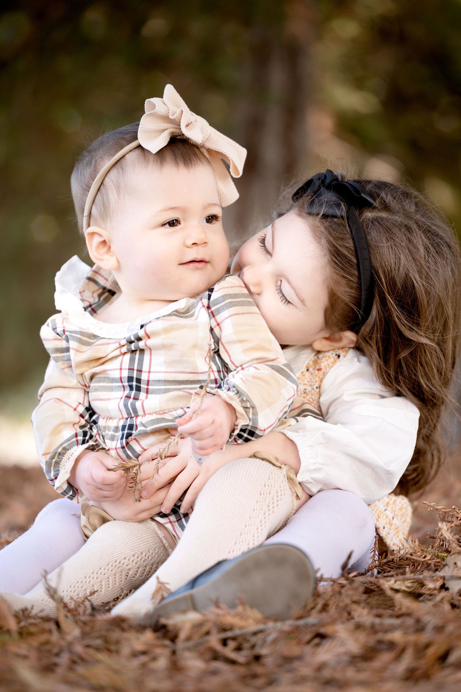 Sweet moment between two children sitting on fallen leaves during autumn photo session.