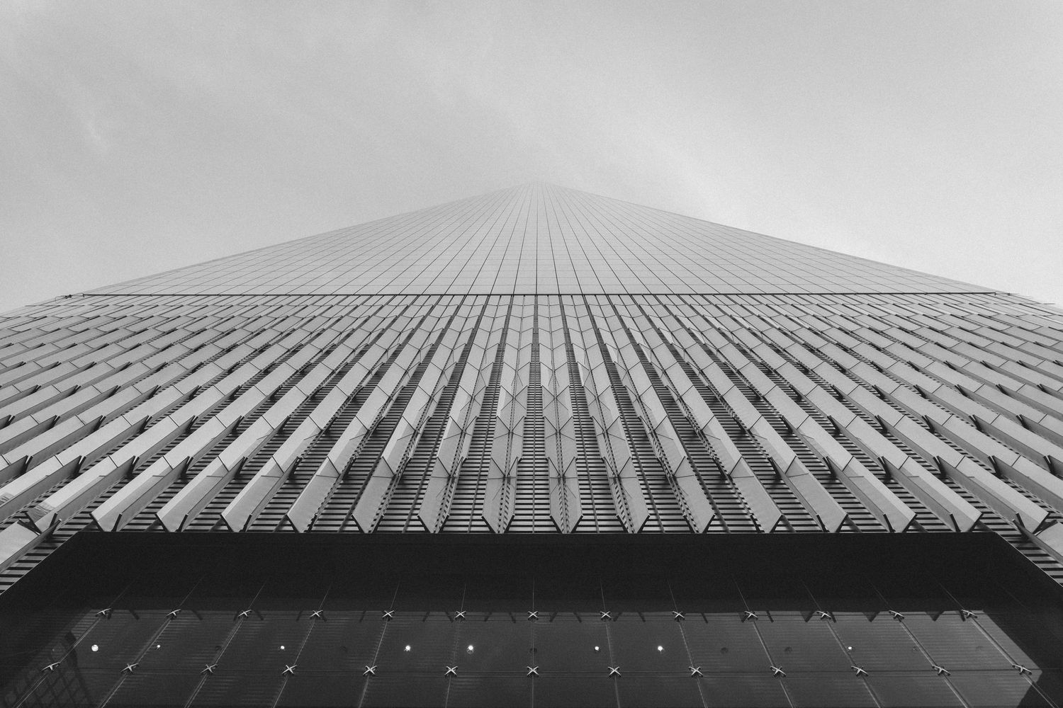 Looking up at modern skyscraper facade with repeating geometric pattern in black and white.
