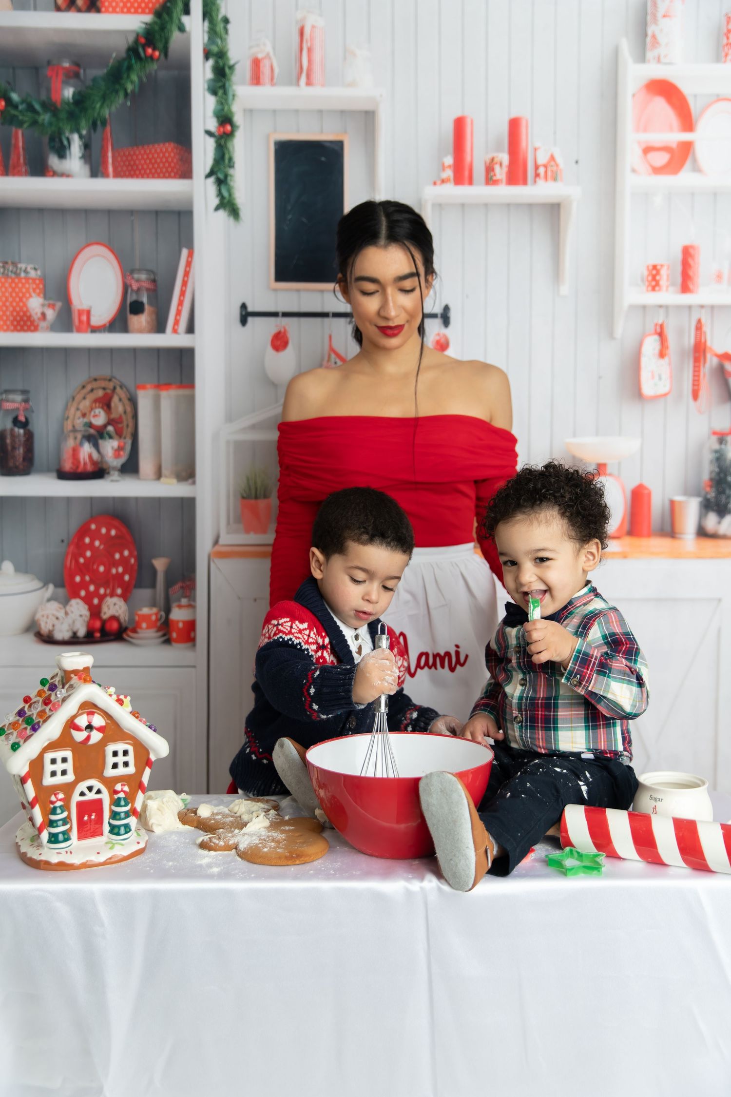 Christmas baking scene with gingerbread house, red and white decor, and festive kitchen setup.