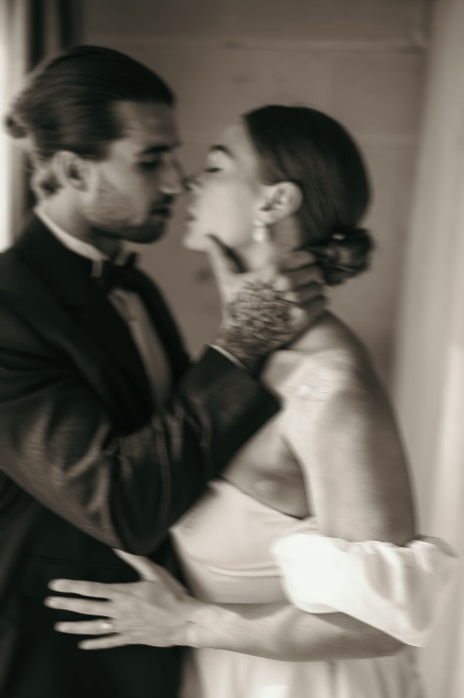 Intimate black and white portrait of couple in formal attire sharing a romantic moment.
