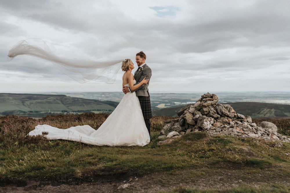 Romantic wedding portrait on a hilltop with dramatic cloudy sky.