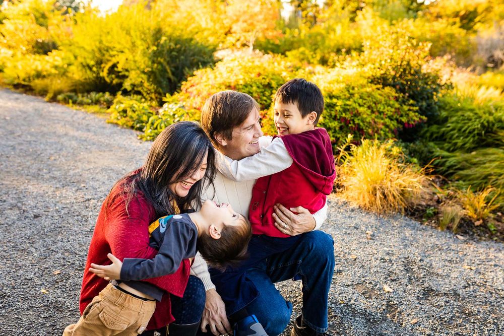 Candid moment of parents playing with their children, backlit, at golden hour