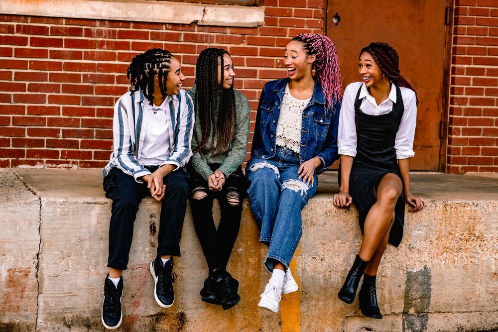 Group of friends sitting casually on brick ledge sharing laughs together.