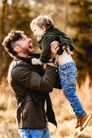 Playful moment between parent and child lifting them up in the air outdoors.