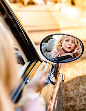Creative side mirror reflection shot of a car during golden hour.