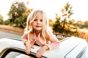 A cheerful moment captured leaning out of a vintage car window.