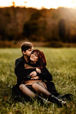 Romantic couple embracing in a sunlit meadow during golden hour.