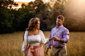 A tender moment captured between two people in a sun-drenched field at sunset.