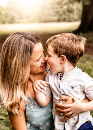 A tender moment between parent and child sharing laughter in an outdoor setting at golden hour.