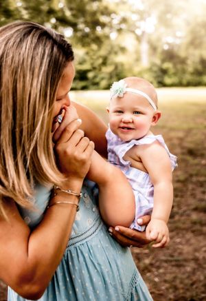 Sweet candid moment captured between parent and baby outdoors with soft natural lighting.