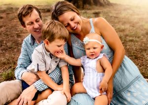 Family of four sharing joyful moment together outdoors at sunset.