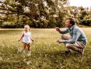 A carefree moment in a grassy field with bubbles floating through the air.