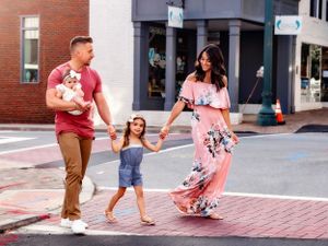 Family strolling together on brick sidewalk in downtown area.
