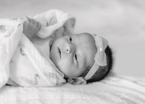 A peaceful black and white portrait of a newborn baby wearing a delicate headband.