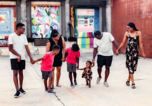 Group of people walking together holding hands along colorful urban wall.