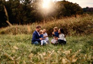 Family sitting together on grass during golden hour sunset.