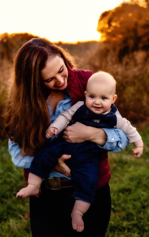 A tender moment between parent and baby during golden hour in a grassy field.