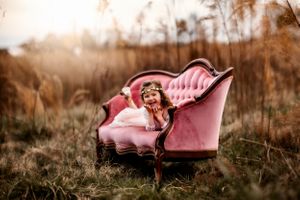 Vintage pink velvet sofa placed outdoors in tall grass during golden hour.