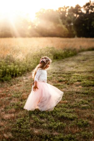 A small dancer twirls in a pink tulle skirt against a golden sunset backdrop.