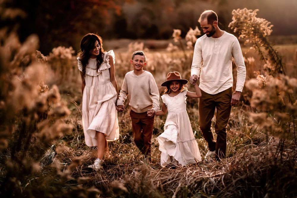 Family walking together through tall grass at golden hour.