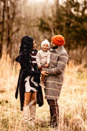 A stylish family shares a loving moment together in a sunlit field during autumn.