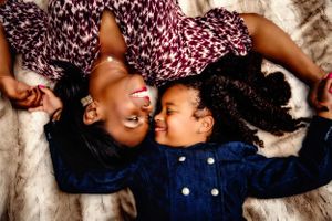 Two people lying down laughing together wearing blue and patterned clothing.