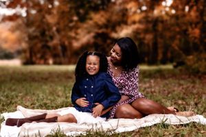 Two people sitting on white blanket in autumn grass.