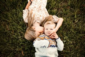 Two people lying on grass wearing cozy winter clothing.