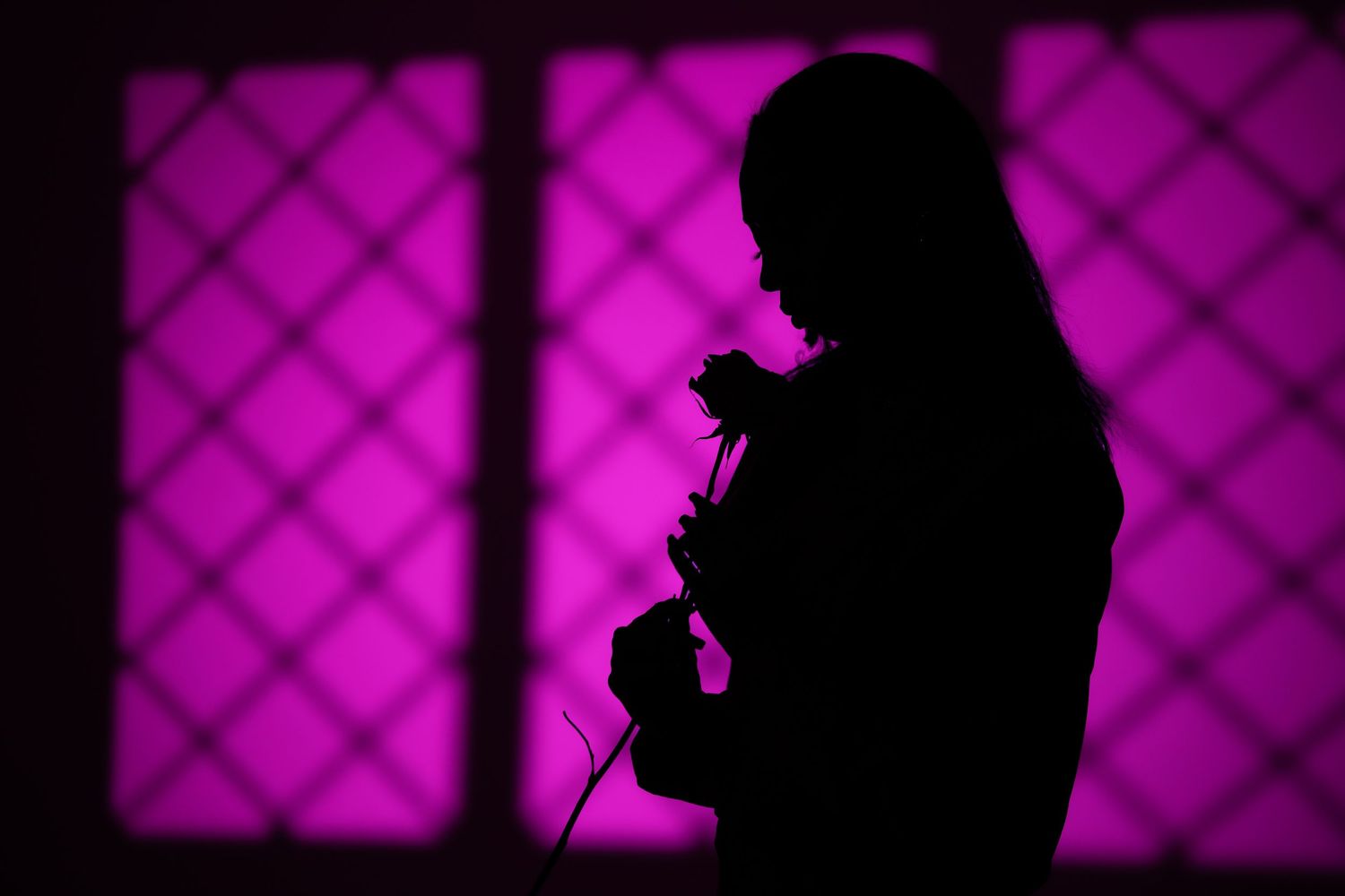 Silhouette of person against vibrant purple backlit geometric pattern.