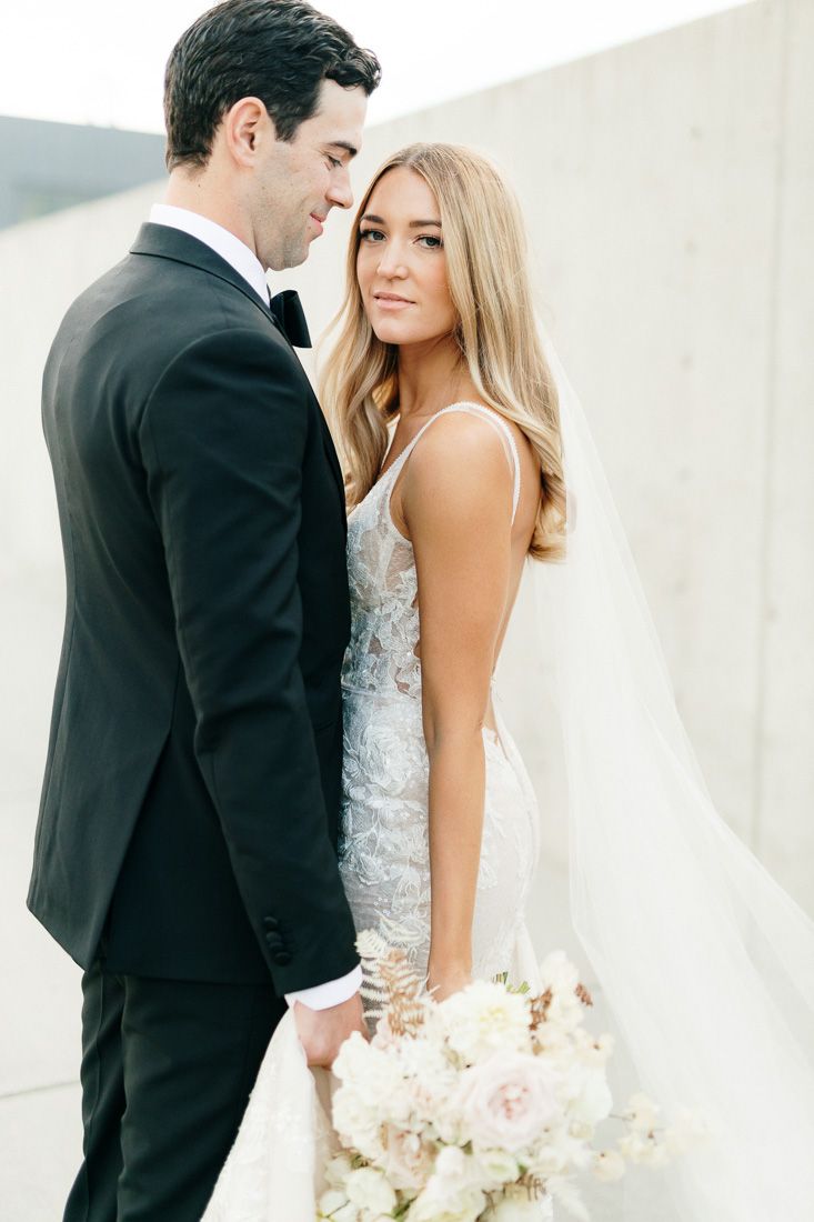 Elegant wedding portrait of a couple in formal attire with a white bouquet.