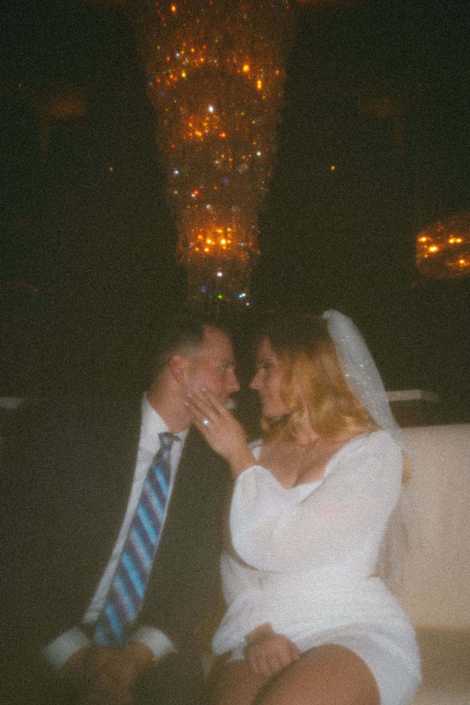 A couple shares an intimate moment under sparkling lights at their wedding reception.