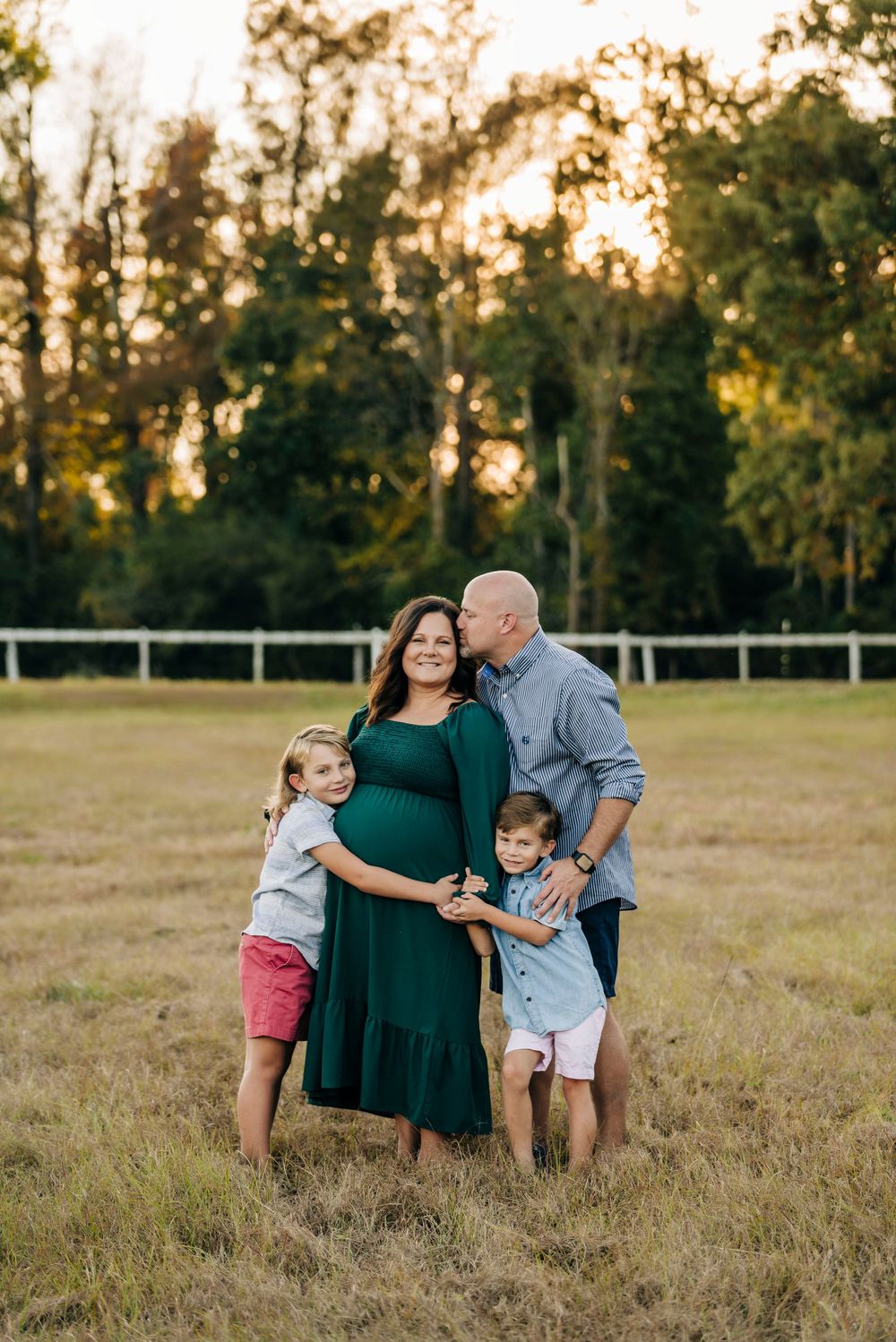 A family shares an intimate moment together in an open field at sunset.