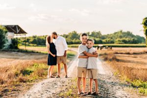 Family members embrace on a dirt path during golden hour photography session.