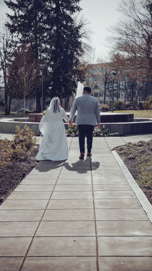 A couple walking on a concrete path surrounded by winter gardens and evergreen trees.